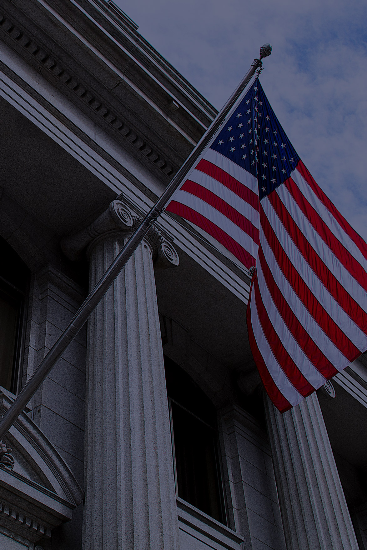 American flag flying from pole in front of columns of a building