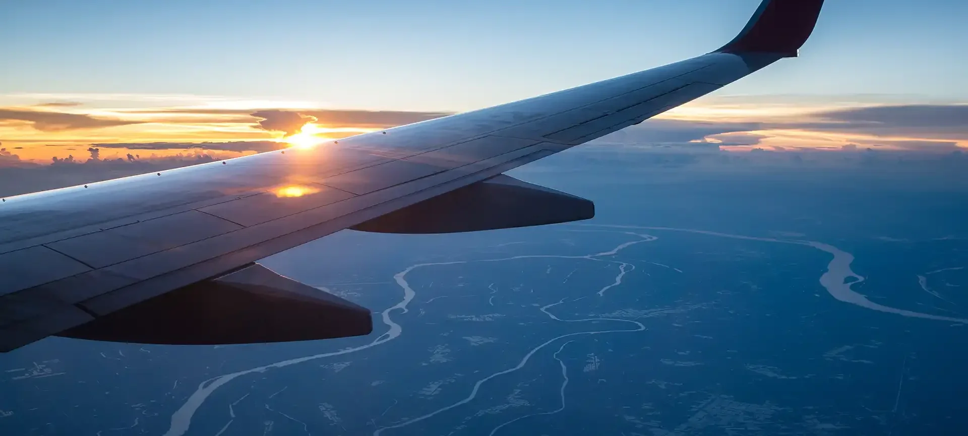 Plane wing flying over a sunset