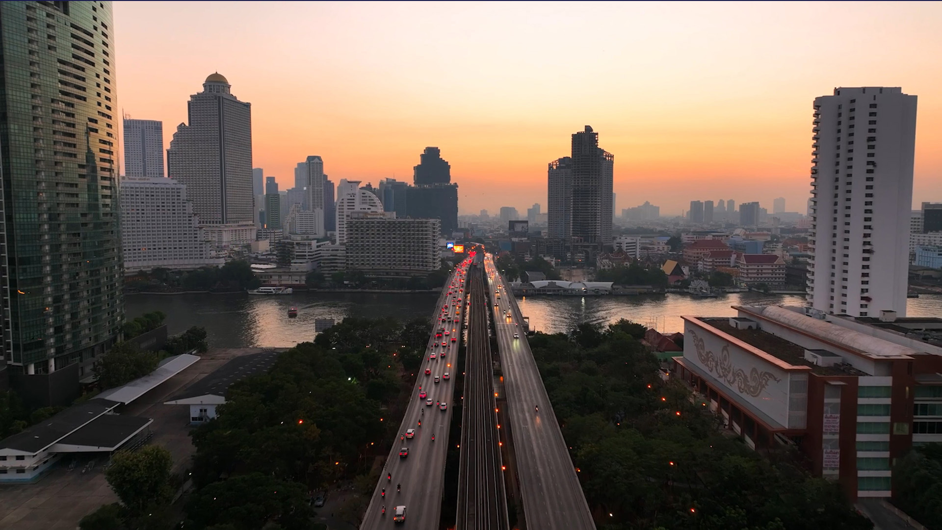 A cityscape at sunset featuring tall buildings and skyscrapers along a river, with a busy highway bridge filled with cars crossing the water. The sky is orange and pink, and the logo troutman pepper locke is visible in the bottom right corner.