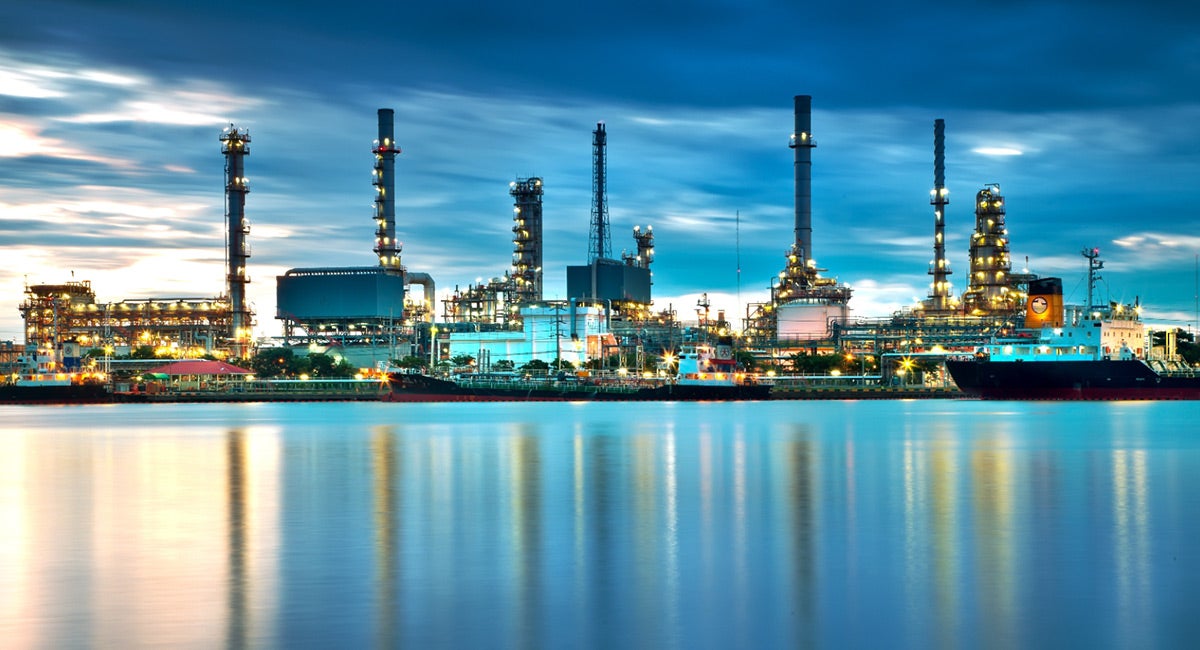 image of an energy plant along the water front at dusk with lights on