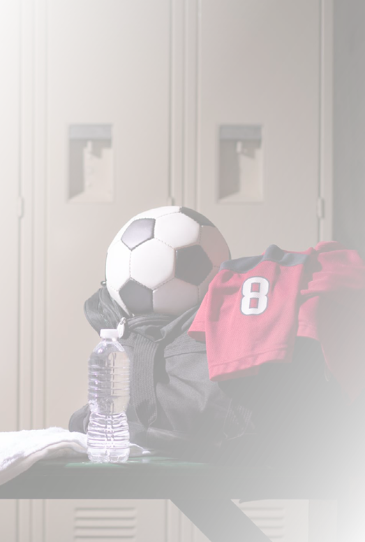 Various sports equipment on bench inside high school or college gymnasium locker room.  Items include: basketball, jersey, water, towel, gym bag..