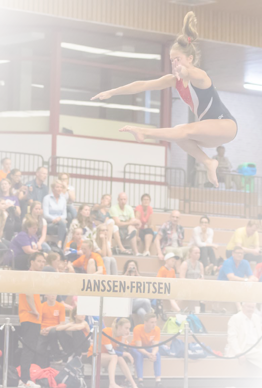 Alkmaar, the Netherlands - June 26, 2015: A young female gymnast is performing her balance beam routine during the International Children Games 2015. She is jumping and captured in the air. ICG is an international sports competition for children between 12 and 15 years old. In 2015 it has been held in Alkmaar.